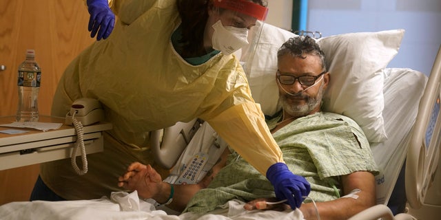 Register nurse Rachel Chamberlin, of Cornish, N.H., left, assists COVID-19 patient Fred Rutherford, of Claremont, N.H. (AP Photo/Steven Senne)