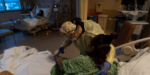 Registered nurse Nvard Termendzhyan helps Linda Calderon, a 71-year-old COVID-19 patient, sit up at Providence Holy Cross Medical Center in Los Angeles. (AP Photo/Jae C. Hong, File)