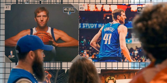 People stand in line to buy memorabilia of former Dallas Mavericks Dirk Nowitzki before an NBA basketball game between the Golden State Warriors and Dallas Mavericks in Dallas, 星期三, 一月. 5, 2022. The Mavericks are retiring Nowitzki's number in a ceremony after the game.