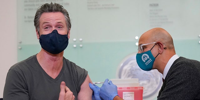 California Gov. Gavin Newsom, left, receives a Moderna COVID-19 vaccine booster shot from California Health and Human Services Secretary Dr. Mark Ghaly at Asian Health Services in Oakland, California, on Oct. 27, 2021. 