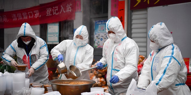 Nesta foto divulgada pela Xinhua, os voluntários usam trajes de proteção para embalar refeições para entrega às pessoas confinadas na cidade de Xi'an, província de Shaanxi no noroeste da China, terça-feira, 4 de janeiro de 2022. (Zhang Bowen / Xinhua via AP)
