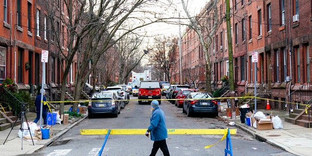 A passer-by looks over the barricade on the street of Wednesday's deadly fire in the Fairmount neighborhood of Philadelphia on Thursday, Jan. 6, 2022. (AP Photo/Matt Rourke)