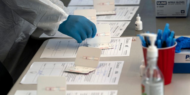 Nurse Ray Akindele processes COVID-19 rapid antigen tests at a testing site in Long Beach , Calif., Thursday, Jan. 6, 2022. (AP Photo/Jae C. Hong)