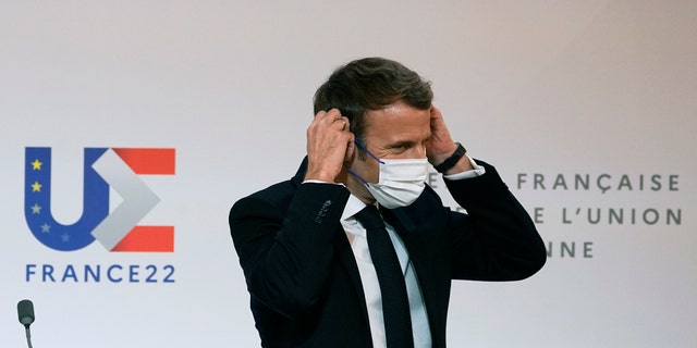 French President Emmanuel Macron puts on his protective mask after participating in a media conference with European Commission President Ursula von der Leyen at the Elysee Palace in Paris, France, Friday, Jan. 7, 2022. (AP Photo/Michel Euler, Pool)