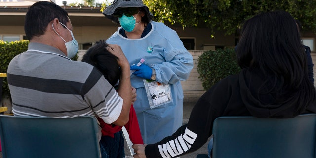 Nurse practitioner Rita Ray collects a nasal swab sample from Sebastian Hernandez, 5, for a COVID-19 test at Families Together of Orange County community health center in Tustin, California, Jan. 6, 2022.