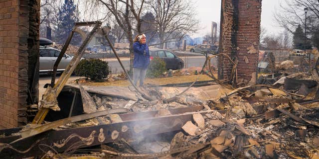 A woman reacts to seeing the remains of her mother's home destroyed by the Marshall Wildfire in Louisville, Colo., Dec. 31, 2021. (AP Photo/Jack Dempsey, File)