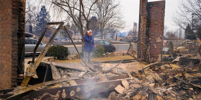 A woman reacts to seeing the remains of her mother's home destroyed by the Marshall Wildfire in Louisville, Colo., Dec. 31, 2021. (AP Photo/Jack Dempsey, File)