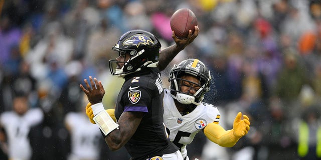 Water sprays off the helmet of Pittsburgh Steelers cornerback Arthur Maulet, reg, as he prepares to make a hit on Baltimore Ravens quarterback Tyler Huntley during the first half of an NFL football game, Sondag, Jan.. 9, 2022, in Baltimore.