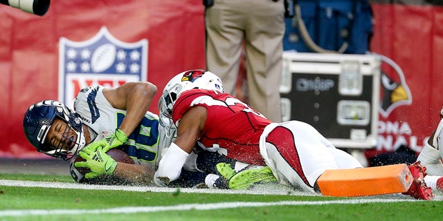 Seattle Seahawks wide receiver Tyler Lockett, left, scores a touchdown as Arizona Cardinals free safety Jalen Thompson, right, makes a late tackle during the first half of an NFL football game Sunday, Jan. 9, 2022, in Glendale, Ariz.