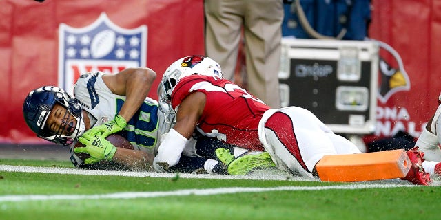Seattle Seahawks wide receiver Tyler Lockett, left, scores a touchdown as Arizona Cardinals free safety Jalen Thompson, right, makes a late tackle during the first half of an NFL football game Sunday, Jan. 9, 2022, in Glendale, Ariz.