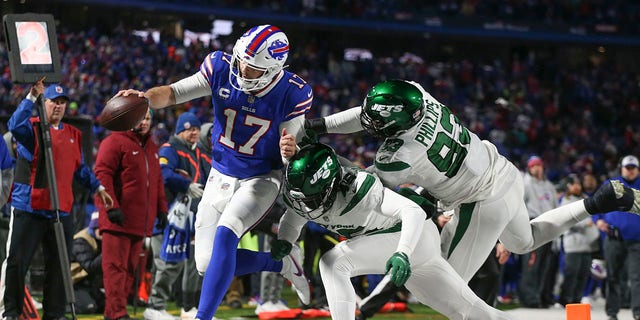 New York Jets defenders push Buffalo Bills quarterback Josh Allen, links, out of bounds during the second half of an NFL football game, Sondag, Jan.. 9, 2022, in Orchard Park, N.Y..