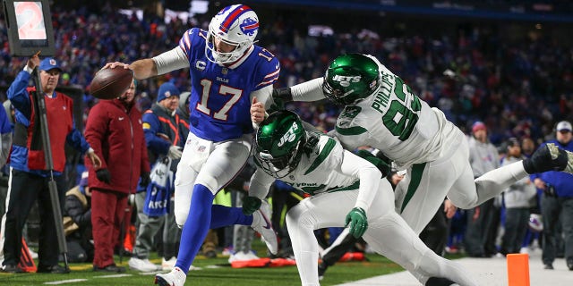 New York Jets defenders push Buffalo Bills quarterback Josh Allen out of bounds during the second half of their game in Orchard Park, N.Y., on Jan. 9, 2022.