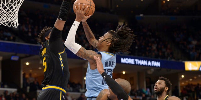 Memphis Grizzlies guard Ja Morant (12) shoots against Golden State Warriors center Kevon Looney (5) and forwards Andre Iguodala (9) and Andrew Wiggins (22) in the second half of a game Jan. 11, 2022, in Memphis, Tenn. 