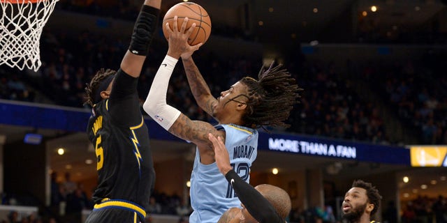 Memphis Grizzlies guard Ja Morant (12) shoots against Golden State Warriors center Kevon Looney (5) and forwards Andre Iguodala (9) and Andrew Wiggins (22) in the second half of a game Jan. 11, 2022, in Memphis, Tenn. 