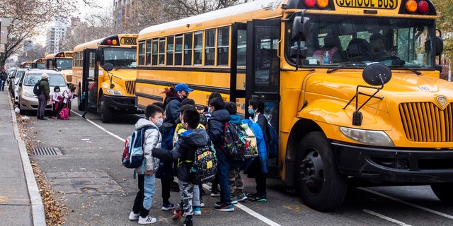Students wearing masks board a school bus outside New Explorations into Science, Technology and Math school, in the Lower East Side neighborhood of New York.