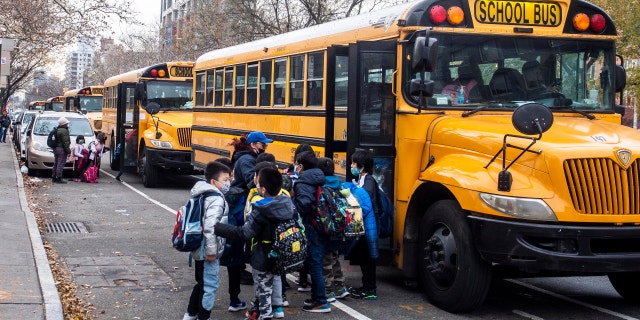 Students wearing masks board a school bus outside New Explorations into Science, Technology and Math school, in the Lower East Side neighborhood of New York.