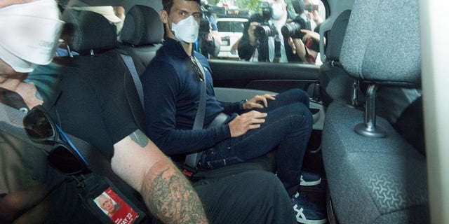 Serbian tennis player Novak Djokovic, center, rides in car as he leaves a government detention facility before attending a court hearing at his lawyers office in Melbourne, Australia, Sunday, Jan. 16, 2022.