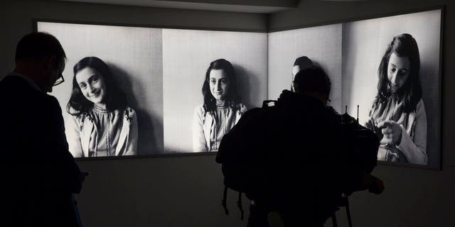 FILE- Journalist takes images of pictures of Anne Frank at the renovated Anne Frank House Museum in Amsterdam, Netherlands, Wednesday, Nov. 21, 2018. A cold case team that combed through evidence for five years may have solved one of World War II's enduring mysteries: Who betrayed Jewish teenage diarist Anne Frank and her family ? Their answer, outlined in a new book, is that it most likely was a Jewish lawyer called Arnold van den Bergh. (AP Photo/Peter Dejong, File)