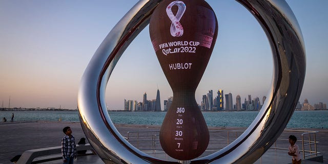 Children stand next to the official countdown clock showing remaining time until the kickoff of the World Cup 2022, in Doha, Qatar, Nov. 25, 2021.