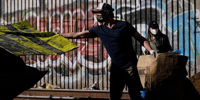California Gov. Gavin Newsom removes cardboard from a Union Pacific railroad site on Thursday, Jan. 20, 2022, in Los Angeles.