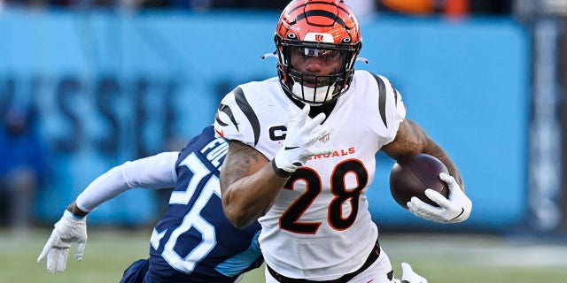 O running back do Cincinnati Bengals, Joe Mixon (28), venceu o cornerback Christian Fulton (26) do Tennessee Titans na primeira metade do jogo de futebol dos playoffs da NFL Division Round no último sábado, 22 de janeiro de 2022, em Nashville, Tennessee.