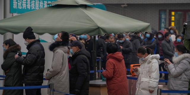 People wearing face masks to help protect from the coronavirus line up to get a swab for the COVID-19 test at a hospital in Beijing, 日曜日, 1月. 23, 2022.
