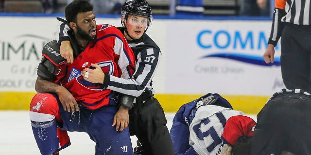After an on-ice fight, South Carolina Stingrays defenseman Jordan Subban (5), 왼쪽, is held by linesman Shane Gustafson while Jacksonville Icemen defenseman Jacob Panetta (15) is face-down on the ice engaged with another player during overtime of an ECHL hockey game in Jacksonville, Fla., 토요일, 1 월. 22, 2022. The ECHL has suspended Panetta after the brother of longtime NHL defenseman P.K. Subban accused the Jacksonville defenseman of making "monkey gestures" in his direction.