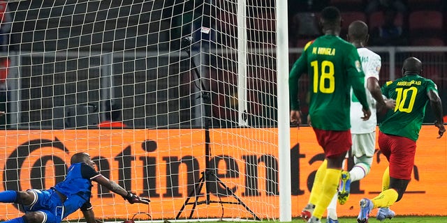 Le gardien de but des Comores Chaker Alhadhur, à gauche, ne parvient pas à arrêter un tir de but du Camerounais Vincent Aboubakar, à l'extrême droite, lors de la ronde de 16 de football de la Coupe d'Afrique des Nations 2022 entre le Cameroun et les Comores au stade Olembe à Yaoundé, Cameroun, lundi janv. 24. 2022.