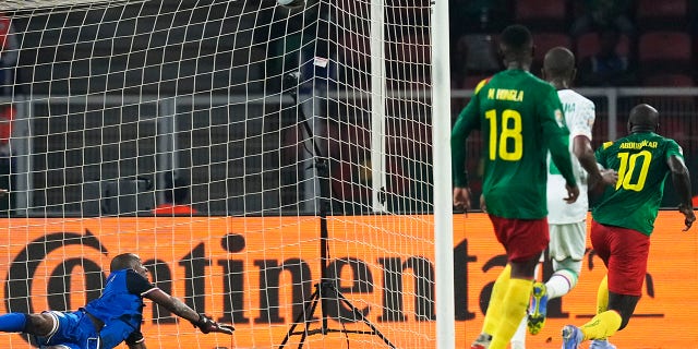 Le gardien de but des Comores Chaker Alhadhur, à gauche, ne parvient pas à arrêter un tir de but du Camerounais Vincent Aboubakar, à l'extrême droite, lors de la ronde de 16 de football de la Coupe d'Afrique des Nations 2022 entre le Cameroun et les Comores au stade Olembe à Yaoundé, Cameroun, lundi janv. 24. 2022.