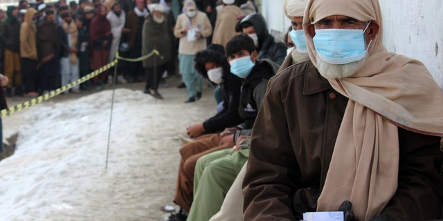 Afghans wait to receive food rations organized by the World Food Program (WFP) in Pul-e-Alam, the capital of Logar province, eastern of Afghanistan, Tuesday, Jan. 18, 2022. (AP Photo/Zubair Abassi)