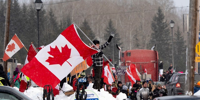 Protesters and supporters against a COVID-19 vaccine mandate for cross-border truckers cheer.
