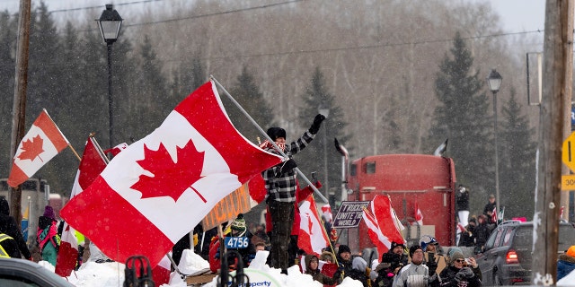 Protesters and supporters against a COVID-19 vaccine mandate for cross-border truckers cheer.