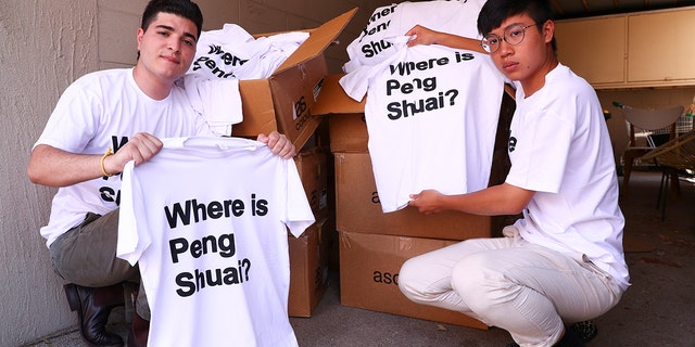 Drew Pavlou, left, and Max Mok show some of the 1,000 shirts they plan to hand out to patrons ahead of Saturday's women's singles final at the Australian Open tennis championships in Melbourne, Australia, Friday, Jan. 28, 2022.