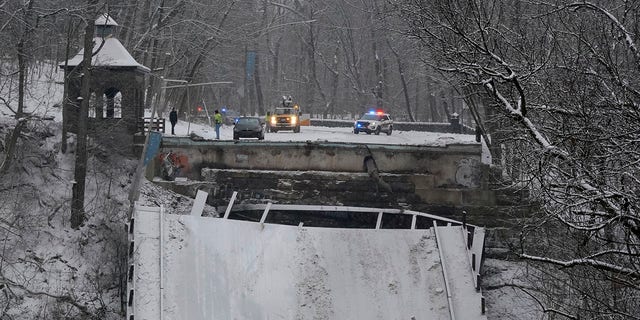 Emergency vehicles are parked at the edge of a bridge that collapsed Friday Jan. 28, 2022, in Pittsburgh's East End. A two-lane bridge collapsed in Pittsburgh early Friday, prompting rescuers to rappel nearly 150 feet while others formed a human chain to help rescue multiple people from a dangling bus. (AP Photo/Gene J. Puskar)