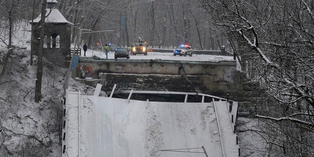 Emergency vehicles are parked at the edge of a bridge that collapsed Friday Jan. 28, 2022, in Pittsburgh's East End. A two-lane bridge collapsed in Pittsburgh early Friday, prompting rescuers to rappel nearly 150 feet while others formed a human chain to help rescue multiple people from a dangling bus. (AP Photo/Gene J. Puskar)