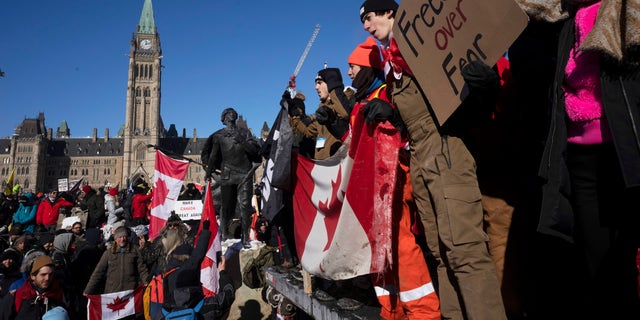 Protesters participating in a cross-country truck convoy protesting measures taken by authorities to curb the spread of COVID-19 and vaccine mandates gather near Parliament Hill in Ottawa on Saturday, Jan. 29, 2022. (Adrian Wyld/The Canadian Press via AP)