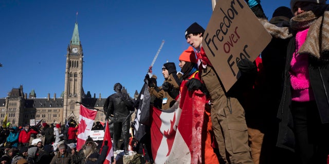 Protesters participating in a cross-country truck convoy protesting measures taken by authorities to curb the spread of COVID-19 and vaccine mandates gather near Parliament Hill in Ottawa on Saturday, Jan. 29, 2022. (Adrian Wyld/The Canadian Press via AP)