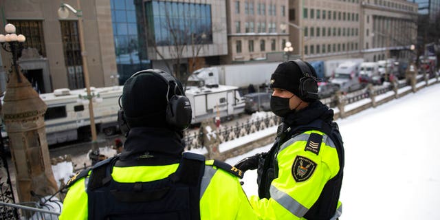 Parliamentary Protective Service officers wear headsets for hearing protection against the sound of truck horns as a rally against COVID-19 restrictions, which began as a cross-country convoy protesting a federal vaccine mandate for truckers, continues in Ottawa, 月曜日に, 1月. 31, 2022. (Justin Tang/The Canadian Press via AP)