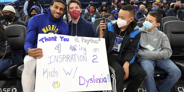 FILE - Golden State Warriors guard Gary Payton II, left, greets young fans from the group Decoding Dyslexia California, before the team's NBA basketball game against the Detroit Pistons in San Francisco, Tuesday, Jan. 18, 2022. Warriors guard Gary Payton II faced daunting challenges reading as a boy because of dyslexia that was diagnosed in second grade. He's now an NBA star with Golden State and he's finding ways to support Bay Area youth with similar learning disabilities to give them tools and courage to push forward when everything feels hard.