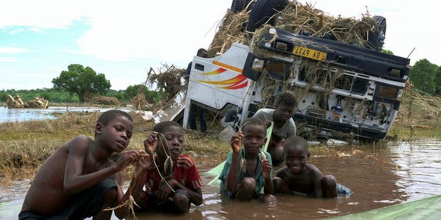 Children show off their catch, near a wreck washed away during tropical storm Ana on the flooded Shire river, an outlet of Lake Malawi at Thabwa village, in Chikwawa district, southern Malawi, Jan. 26, 2022. (REUTERS/Eldson Chagara)