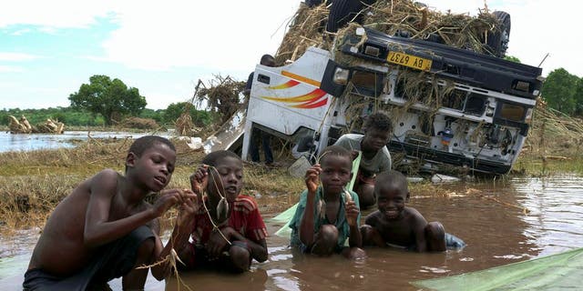 Children show off their catch, near a wreck washed away during tropical storm Ana on the flooded Shire river, an outlet of Lake Malawi at Thabwa village, in Chikwawa district, southern Malawi, Jan. 26, 2022. (REUTERS/Eldson Chagara)