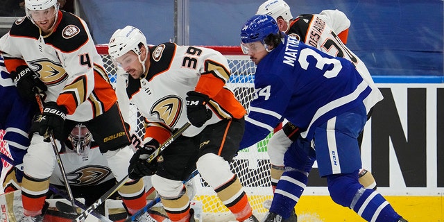 Anaheim Ducks' Sam Carrick (39) and Toronto Maple Leafs' Auston Matthews (34) look for the loose puck during the first period of an NHL hockey game in Toronto on Wednesday, Jan 26, 2022.