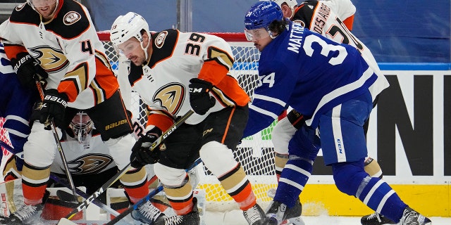 Anaheim Ducks' Sam Carrick (39) and Toronto Maple Leafs' Auston Matthews (34) look for the loose puck during the first period of an NHL hockey game in Toronto on Wednesday, 1 월 26, 2022.
