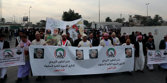 Halk Seferberlik Güçleri destekçileri ve üyeleri, 1 Ocak 2022 Cumartesi günü Bağdat, Irak'ta güçlü bir İranlı generalin ve üst düzey bir Iraklı milis liderinin posterlerini taşıyorlar. 
