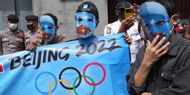 Student activists wear masks with the colors of the pro-independence East Turkistan flag during a rally to protest the Beijing 2022 Winter Olympic Games outside the Chinese Embassy in Jakarta, Indonesia, Friday, Jan. 14, 2022.