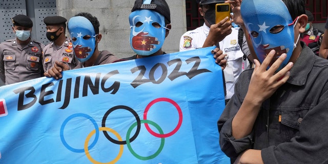 Aktivis mahasiswa mengenakan topeng dengan warna bendera Turkistan Timur pro-kemerdekaan selama demonstrasi untuk memprotes Olimpiade Musim Dingin Beijing 2022 di luar Kedutaan Besar China di Jakarta, Indonesia, Jumat, 1 Januari.  14, 2022.