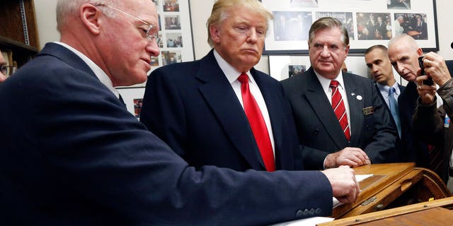 FILE— New Hampshire Secretary of State Bill Gardner, left, talks with Republican presidential candidate Donald Trump as Trump files his papers to be on the nation's earliest presidential primary ballot, Wednesday, Nov. 4, 2015, at the Statehouse in Concord, N.H. (AP Photo/Jim Cole, File)