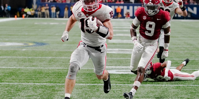 LÊER - Georgia tight end Brock Bowers (19) runs into the end zone for a touchdown against Alabama defensive back Jordan Battle (9) during the second half of the Southeastern Conference championship NCAA college football game, Saterdag, Des. 4, 2021, in Atlanta. Georgia plays Alabama in the College Football Playoff national championship game on Jan. 10, 2022.