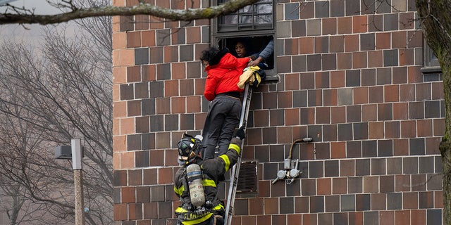 Firefighters hoisted a ladder to rescue people through their windows after a fire broke out inside a third-floor duplex apartment at 333 E. 181st St. in the Bronx Sunday. (Theodore Parisienne/New York Daily News/Tribune News Service via Getty Images)