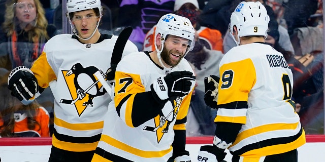 Pittsburgh Penguins' Evan Rodrigues (9), Bryan Rust (17) and John Marino (6) celebrate after a goal by Rust during the first period of an NHL hockey game against the Philadelphia Flyers, Thursday, Jan. 6, 2022, in Philadelphia.